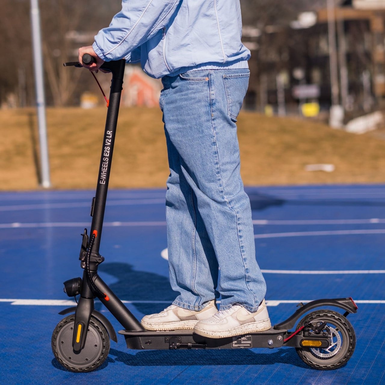 E-Wheels E2S V2 Long Range el-sparkesykkel i svart p&aring; en bl&aring; ballbane